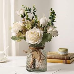 a vase filled with white flowers sitting on top of a table next to two books