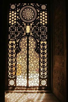 an ornate iron door with intricate carvings on the outside and inside doors are lit by sunlight coming through them