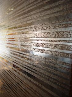 the sun shines brightly through an intricately designed glass window with metal slats