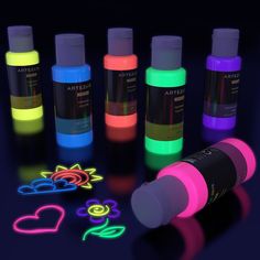 an array of fluorescent ink bottles and neon stickers on a dark background with hearts