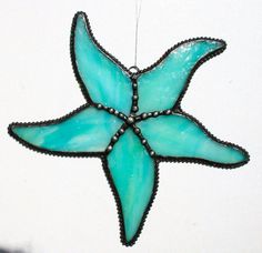 a blue stained glass star ornament hanging from a hook on a white wall