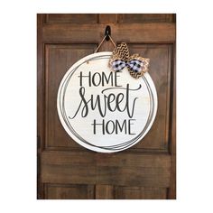 a wooden sign that says home sweet home hanging on the front door with a bow