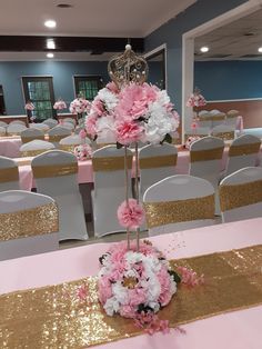 pink and white flowers are on top of a table in a banquet room with gold sequins