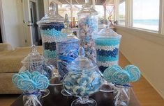 a table topped with lots of blue and white candies on top of glass vases