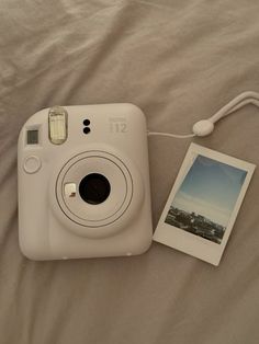 a polaroid camera sitting on top of a bed next to an instax photo