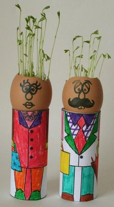 two eggs decorated like people with plants in them