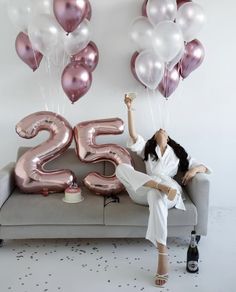 a woman sitting on a couch with balloons and the number twenty five