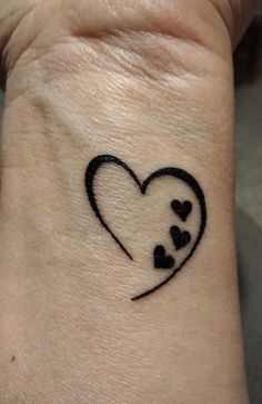 a small heart tattoo on the wrist that is black and has hearts drawn across it