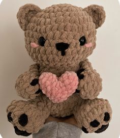 a crocheted teddy bear holding a pink heart