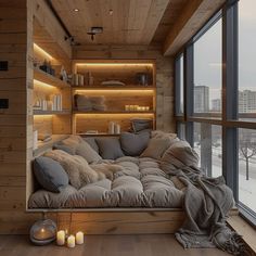 a couch sitting in front of a window next to a wooden wall with shelves filled with books