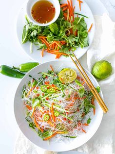 two white plates filled with vegetables and some chopsticks next to each other on a table