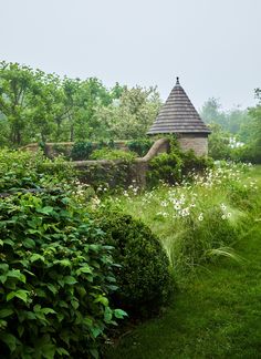 an old stone building surrounded by lush green bushes