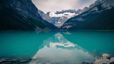 a lake surrounded by mountains and rocks in the foreground