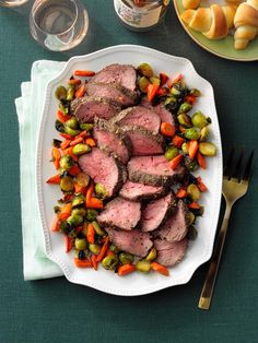 a plate with steak, potatoes and tomatoes on it next to a knife and fork