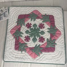 a close up of a quilt on a bed with a white and pink design in the center