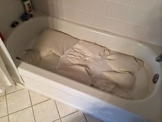 a bathtub filled with toilet paper next to a tiled wall and floor in a bathroom