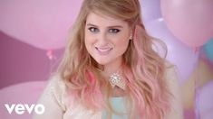 a woman with long blonde hair and blue eyes standing in front of some pink balloons