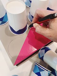 a person is painting some cups on a table