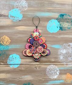 an ornament hanging from a string on top of a wooden surface with paint splatters