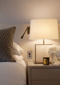 a nightstand with a lamp and flowers on it