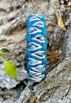 a blue and white bracelet sitting on top of a tree branch in front of some rocks