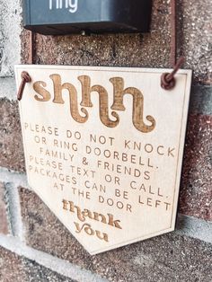 a wooden sign hanging on the side of a brick building