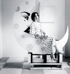 a woman sitting on top of a chair in front of a wall with circles and birds