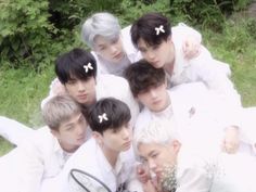 a group of young men sitting next to each other on top of a lush green field