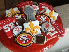 a football themed cake on a red plate with white frosting and gold fleur de lis decorations