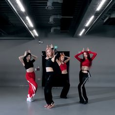 three young women in red and black outfits are doing dance moves with their hands up