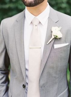 a man wearing a suit and tie with a boutonniere on his lapel