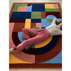 a woman laying on top of a colorful rug in the middle of an area with circles