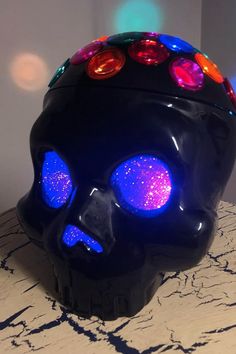 a black skull with colorful lights on it's head sitting on top of a table