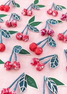 red and blue cherries with green leaves on a pink tablecloth covered in candy