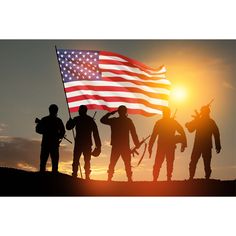 silhouettes of soldiers holding american flag at sunset