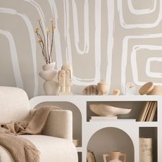 a living room filled with furniture and vases on top of a white shelf next to a wall