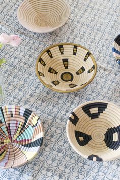 four woven baskets sitting on top of a blue and white cloth covered table next to a vase with flowers in it