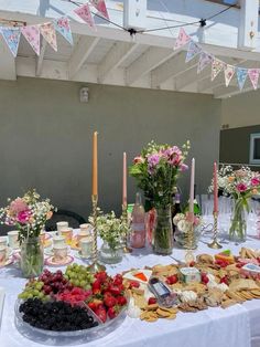 a table topped with lots of food next to tall candles and vases filled with flowers