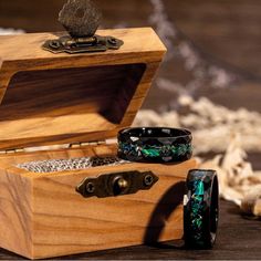 a wooden box with two rings in it on a table next to shells and other items