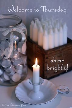 a candle is sitting on a plate next to a glass jar filled with white candles