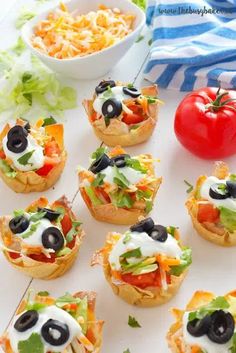 small appetizers with olives, tomatoes and lettuce are arranged on a white plate