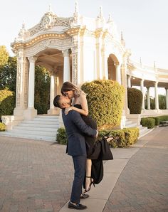 a man and woman are kissing in front of a gazebo with steps leading up to it