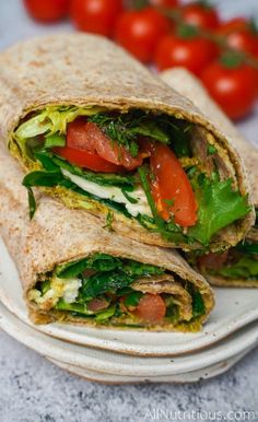 a wrap with lettuce, tomatoes and other veggies is on a plate