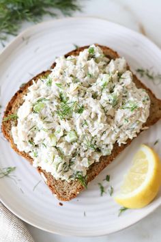 a white plate topped with a piece of bread covered in cream cheese and dill