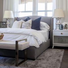 a bedroom with a large bed and two lamps on either side of the window sill