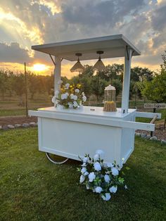 a small white shrine with flowers on the grass and lights in the sky above it