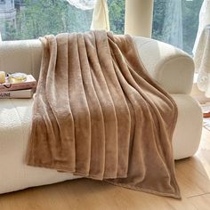 a couch with a blanket on top of it next to a book and some books