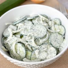 a white bowl filled with cucumbers on top of a table