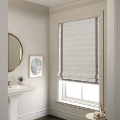 a bathroom with a sink, mirror and window coverings on the windows sill