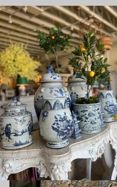 several blue and white vases on a table with a potted tree in the middle